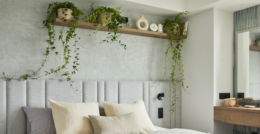 Urządzona ściana za łóżkiem z półką i kwiatkami